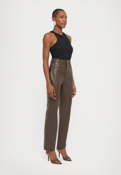 Black sleeveless top, brown leather high-waisted pants, fitted silhouette, smooth texture, paired with open-toe brown heels, simple silver earrings.