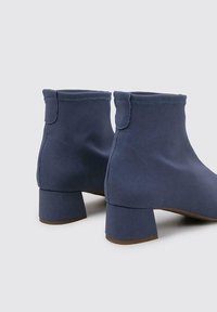 Bottines en tissu bleu avec un talon bloc, texture lisse et couture simple. Présentent un bout arrondi et un ajustement serré en haut.