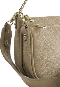 Beige leren handtas met textuur, gouden hardware, een kettingriem en dubbele ritscompartimenten. Opvallende stiksels langs de randen.