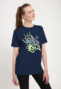 Námořnická modrá bavlněná tričko s grafikou stylizovaného dodávkového auta a zelenými graffiti podobnými akcenty. Krátké rukávy a pohodlný střih.