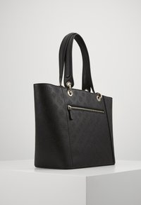 Schwarze strukturierte Tragetasche mit zwei Griffen, goldenen Hardware-Details, vorderer Reißverschlusstasche und geprägtem Design auf der gesamten Fläche.