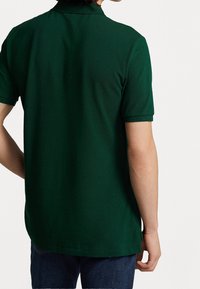 Zielona koszulka polo z klasycznym kołnierzykiem, krótkimi rękawami i prostym dołem. Materiał z mieszanki bawełny o gładkiej teksturze. Widok z tyłu.