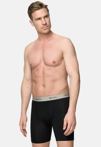 Svarta boxerkalsonger med midjeband i grått som har diskret logotyp, tillverkade av mjukt, andningsbart tyg, som ger en åtsittande passform och en enkel design.