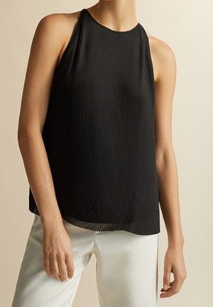 Haut sans manches noir avec un col haut et une texture côtelée, associé à un pantalon blanc à jambes larges. Détail notable : ourlet transparent.