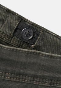 Pantalones de mezclilla de color gris oscuro con cierre de botón de diseño de cuatro agujeros, tela texturizada y costuras visibles a lo largo de la cintura.