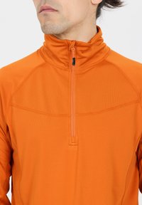 Orange Viertel-Reißverschluss-Trikot für Sport mit hohem Kragen, ausgestattet mit einem strukturierten Stoff und kontrastierenden Reißverschlussdetails.