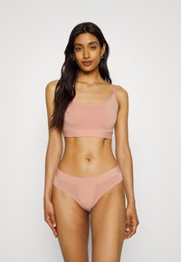 Light pink bra and matching brief set made from smooth fabric. The bra features thin straps and a seamless design, while the brief has a soft waistband.