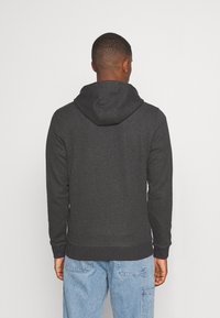 Felpa con cappuccio grigio scuro in tessuto texture, con polsini e vita a costine, dotata di tasca a marsupio e cappuccio con coulisse regolabile.