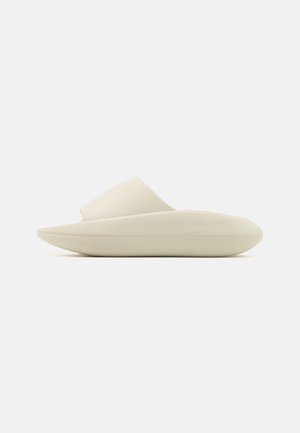 Sandal de deslizar de cor clara com um acabamento liso e mate. Apresenta um design minimalista com uma sola curva e uma tira larga para fácil uso.