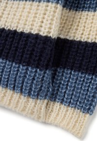 Primo piano di un tessuto lavorato a maglia che mostra delle righe orizzontali nei colori crema, blu scuro e blu, con una texture a coste.