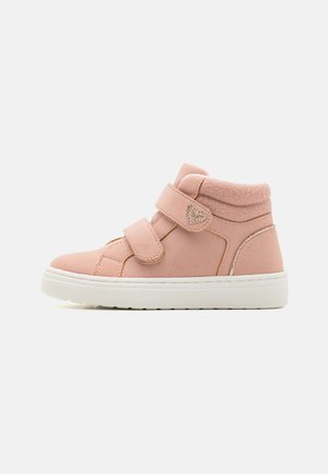 Scarpe high-top rosa con due cinturini in velcro, tomaia in tessuto morbido, suola in gomma bianca e un accento decorativo a forma di cuore sul lato.