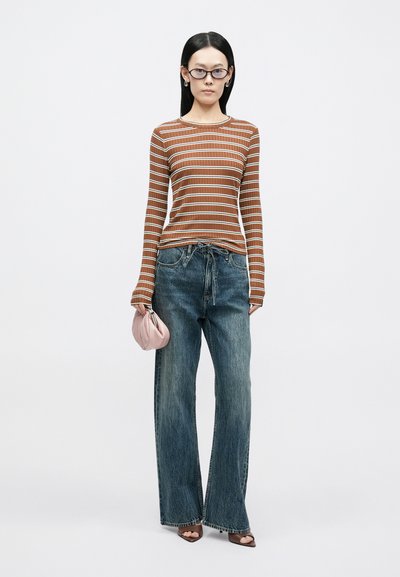 Top de manga comprida às riscas castanhas, jeans azuis de perna larga, mala cor-de-rosa, sapatos castanhos de salto alto. Textura suave, design casual, ajuste solto.