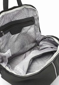 Interior de una bolsa de tela negra perforada que muestra un forro gris claro con patrones de texto circulares y un bolsillo con cremallera.