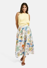 Gelbtäuferungsoberteil ohne Ärmel, kombiniert mit einem gemusterten, knielangen Rock, der bunte Designs wie Sonnen, Blumen und abstrakte Formen zeigt.