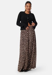 Černý cardigan s knoflíkovým zapínáním v kombinaci s volnou maxi sukní s leopardím potiskem. Vlněná textura, volný střih a poloprůhledná látka.