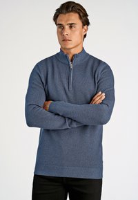 Niebieski, zapinany na zamek sweter z dzianiny o teksturowanym wzorze, z prążkowanymi mankietami i dolnym obszyciem. Posiada stójkę oraz widoczny detal zamka.