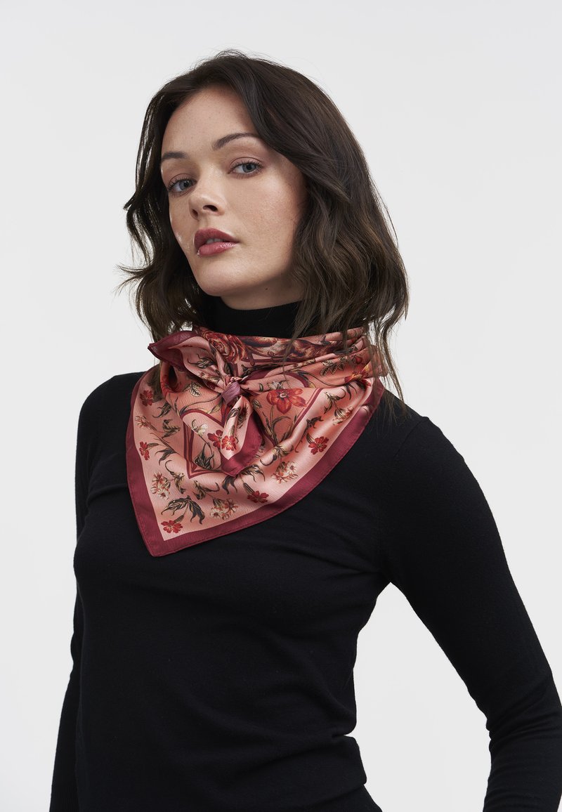 Silk tørklæde i blush pink med blomstermønster, trekantet design og en knyttet accent. Har en glat, blank tekstur og kontrasterende kanter.