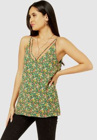 Floral tank top in green with multi-colored rose patterns. Features thin straps, a V-neckline, and a relaxed fit. Paired with black pants.