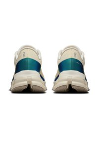 White and teal athletic shoes with a textured upper, cushioned sole, and a smooth finish. Features logo on the heel and structured back.