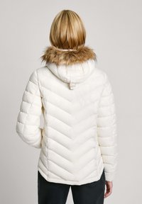 Crème-kleurige pufferjack met een chevronpatroon, voorzien van een faux fur-voering in de capuchon en een verstelbare band, ontworpen voor warmte.