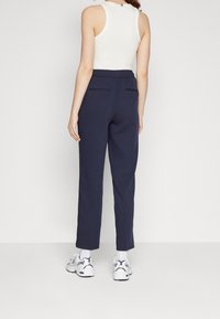 Pantalones de sarga ajustados color marino, fabricados en un tejido suave, con una cintura elástica, dos bolsillos traseros y un acabado limpio en los puños.