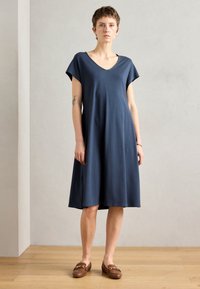 Navy blue cotton dress with short sleeves, V-neckline, relaxed fit, and knee-length skirt. Worn with brown loafers. Smooth texture.