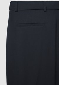 Navyblaue, maßgeschneiderte Hose mit glatter Textur, ausgestattet mit einem schmalen Bund und einer einzelnen Gesäßtasche. Dezentes diagonales Muster auf dem Stoff.