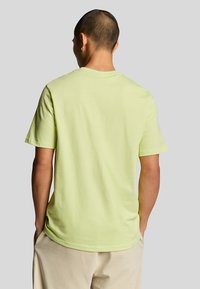 T-shirt a maniche corte di un vivace verde neon, realizzato in morbido cotone, con un classico scollo tondo e una vestibilità comoda. Vista posteriore mostrata.