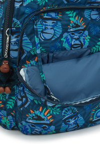Blå stof rygsæk med farverige gorillaprints, der har en lynlåslomme, grønne detaljer og en blød gorillanøglekæde.