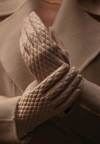 Quilted leather gloves in a light taupe color, featuring diagonal stitching patterns and a smooth texture, held together in a closed position.
