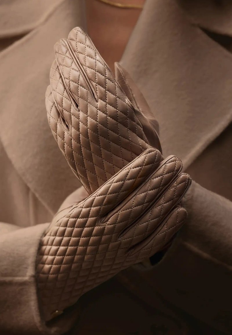 Quilted leather gloves in a light taupe color, featuring diagonal stitching patterns and a smooth texture, held together in a closed position.