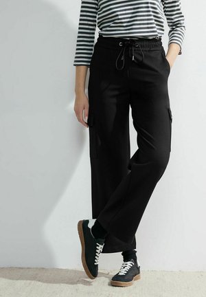Zwarte cargobroek met een relaxed fit, voorzien van zijzakken, een verstelbare taille, gecombineerd met een gestreepte lange mouwen top en sneakers.
