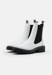 Botines Chelsea de cuero blanco con paneles elásticos laterales negros, suela de goma negra gruesa y detalles de costura en blanco en contraste.