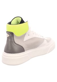 Hochformat Sneaker mit einem weißen Lederkörper, grauem strukturiertem Fersenbereich und einem leuchtend gelben Kragen. Verfügt über flache Schnürsenkel und ein rundes Detail an der Ferse.
