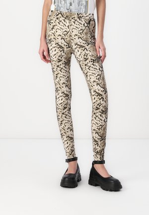 Leggings stampati zebrati in beige e nero con un design aderente, dotati di una texture liscia e di una vita elasticizzata. Combinati con scarpe nere chunky.