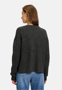 Ciemnoszary sweter dzianinowy o luźnym kroju i obniżonych ramionach, z prążkowanymi mankietami i okrągłym dekoltem. Miękka tekstura.