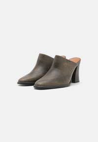Muli din piele maro, cu vârf deschis, cu un design elegant, vârf ascuțit și un toc bloc robust. Textură subtilă și detalii de coasere contrastante.