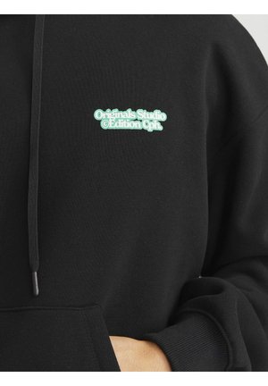Sort sweatshirt med en frontlomme, snorhætte og grønt broderet logo, der står "Originals Studio © Edition Cph" på brystet.