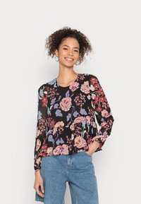 Blusa preta com padrão floral e mangas longas, apresentando um design peplum e padrões de flores rosas e azuis sobre um fundo escuro.