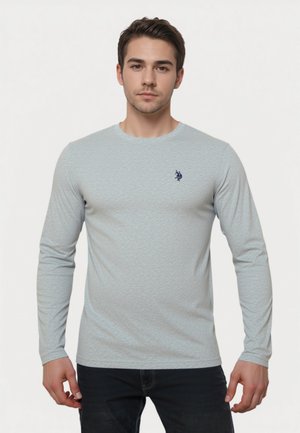 Világoskék, hosszú ujjú póló, texturált anyagból, kerek nyakkivágással, és egy kis sötétkék logóval a bal mellrészen.