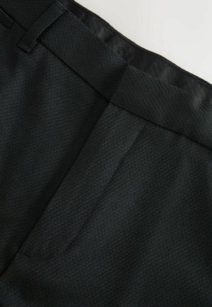 Ciemnozielone, dopasowane spodnie z teksturowanej tkaniny. Posiadają gładki pas i głębokie kieszenie, prezentując czysty, minimalistyczny design.