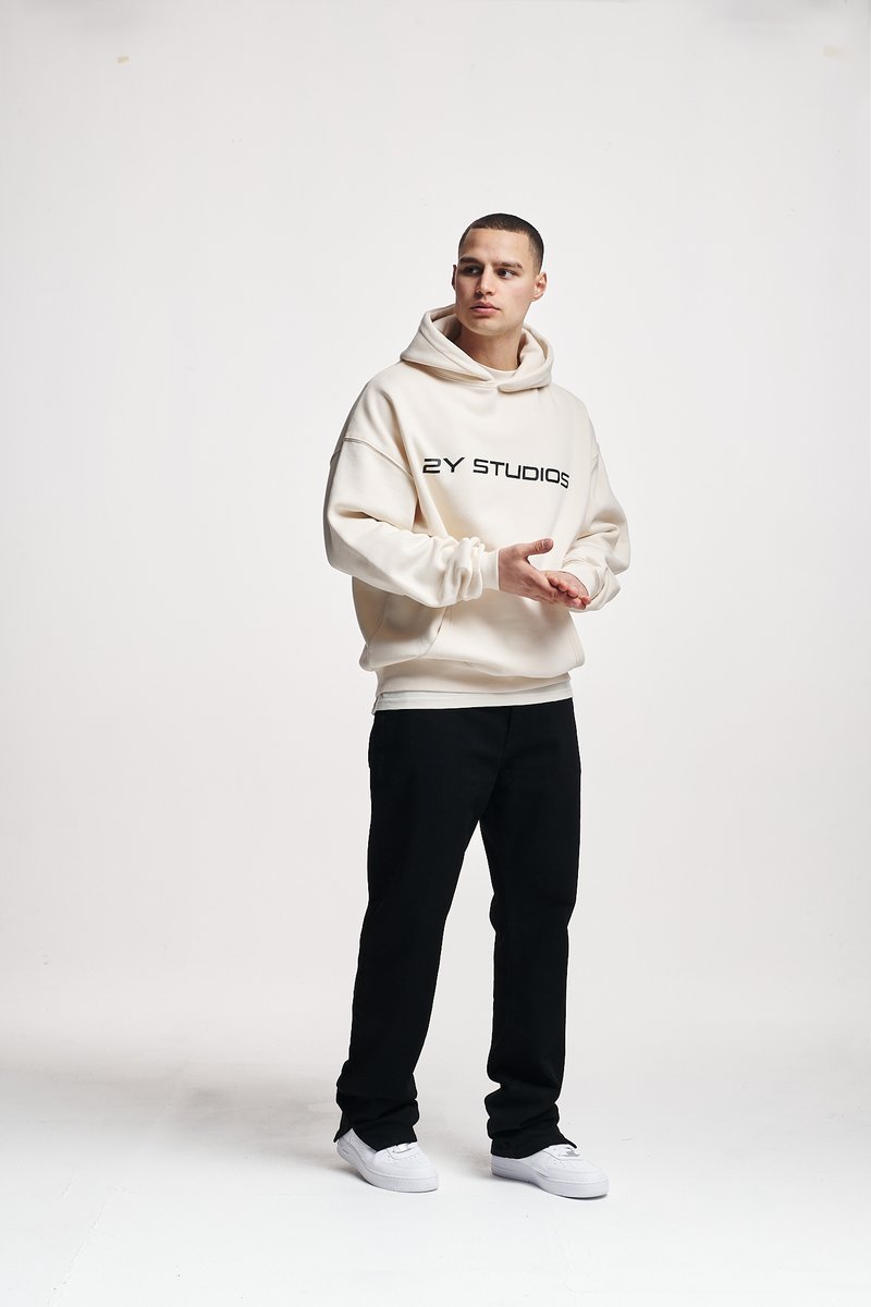 Sweatshirt crème avec "2Y STUDIOS" en texte noir, associé à un pantalon noir et des baskets blanches ; coupe décontractée et texture douce.