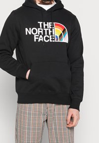 Felpa nera in cotone con una grafica arcobaleno multicolore e il testo "THE NORTH FACE" sul davanti; tasca a marsupio e cappuccio con cordino.