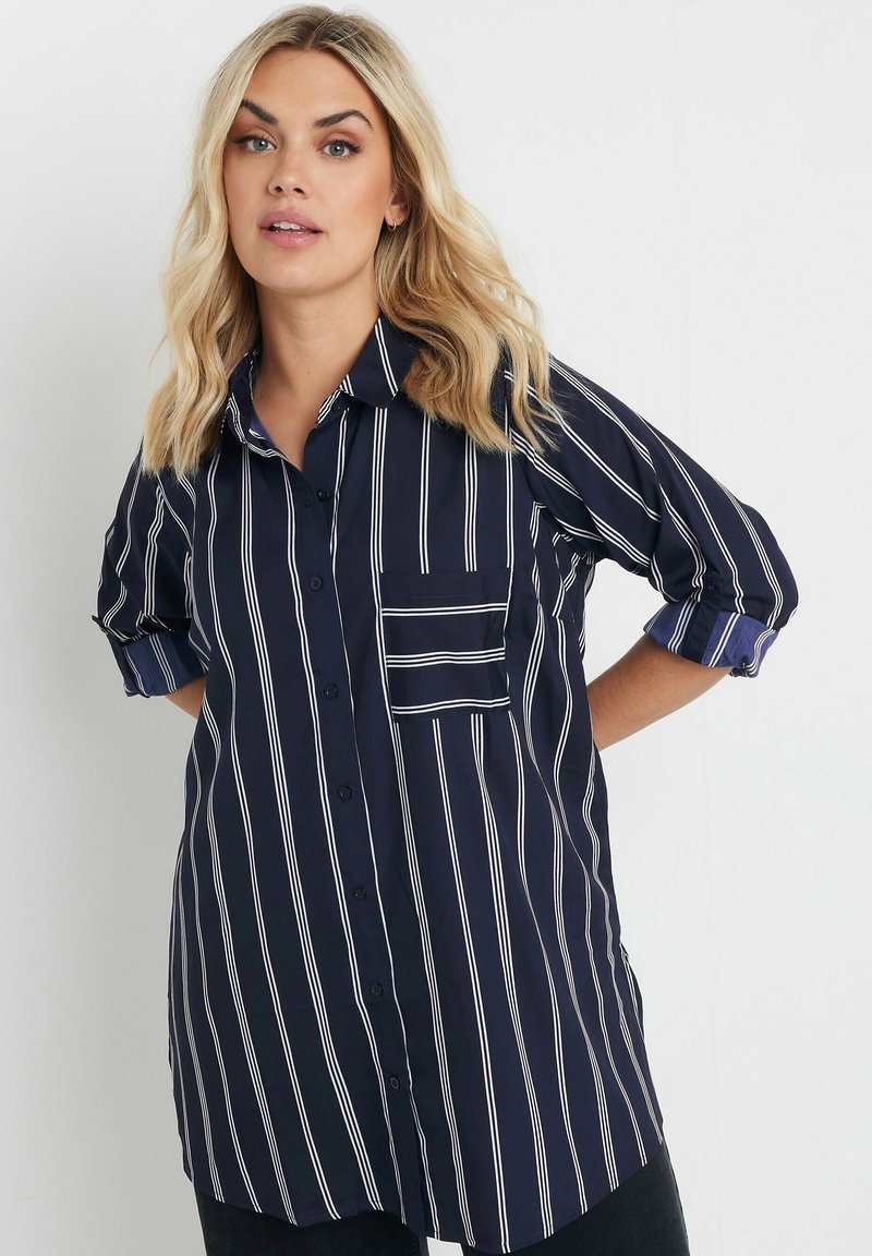 Camicia blu con bottoni, a righe verticali bianche, con maniche corte arrotolate e tasca sul petto. Tessuto morbido con una vestibilità comoda.