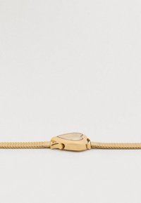 Kulla tooni südamekujulise korpusega käekell võrgumustri rihmaga. Kella ees on läbipaistev kate ja minimalistlik disain, mis rõhutab elegantset, säravat tekstuuri.