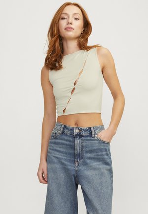Top cropped senza maniche di un verde chiaro, con design asimmetrico e dettagli cut-out, abbinato a jeans in denim blu a vita alta.
