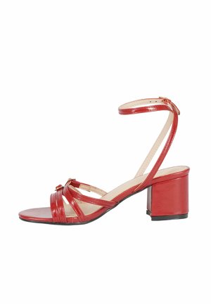 Sandal in pelle verniciata rossa con più cinturini, cinturino alla caviglia e tacco quadrato chunky. La suola è nera con una finitura liscia.