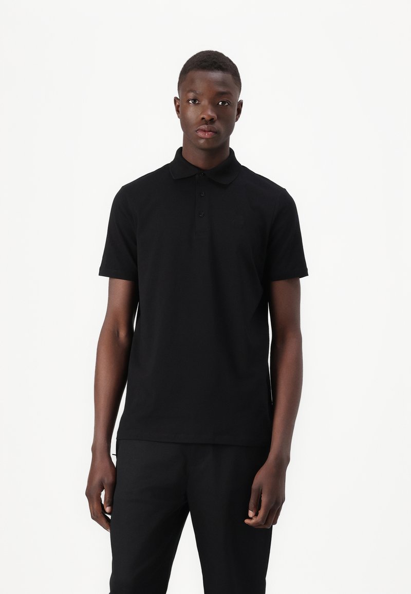 Black polo shirt made of smooth cotton. Features a classic collar, short sleeves, and three-button placket. Subtle logo on the chest.