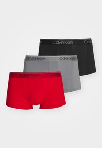 Drei Paar Herrenboxershorts in einem rot, grau und schwarz Farbdesign. Jedes Paar hat ein Calvin Klein Logo am Bund.