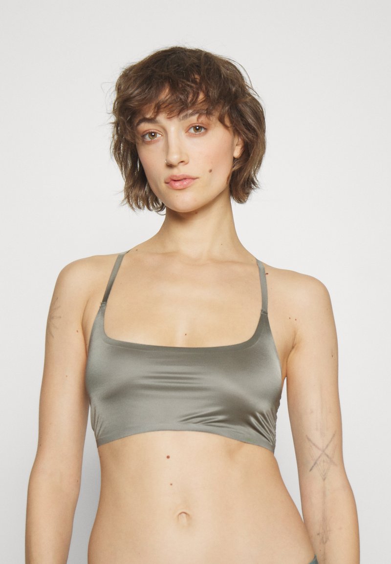 Elegantan maslinasto zeleni bralette, izrađen od glatkog materijala. Ima tanke podesive naramenice i prilagođeni, kvadratni dekolte. Minimalistički dizajn.